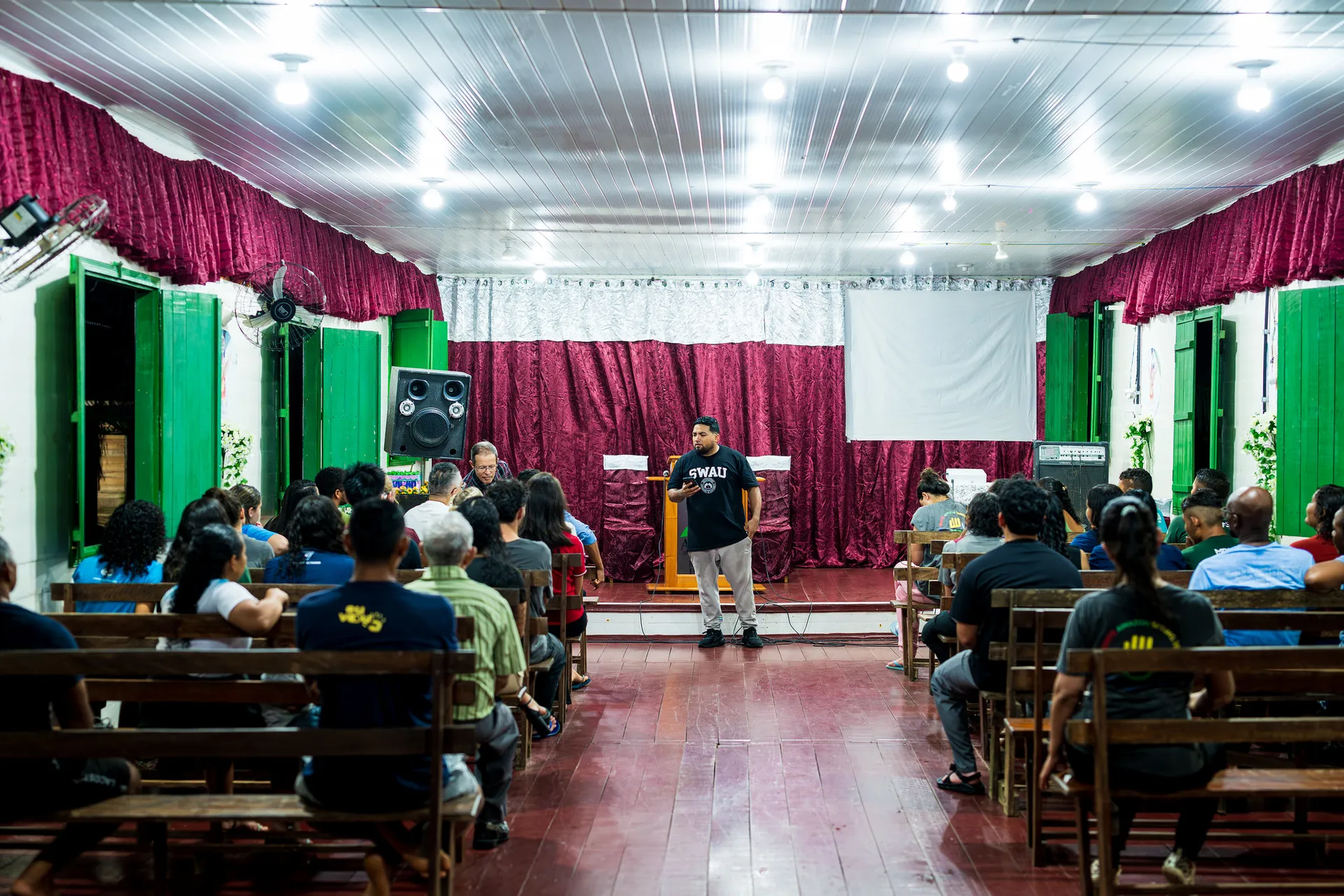 A man preaching in front of a small church