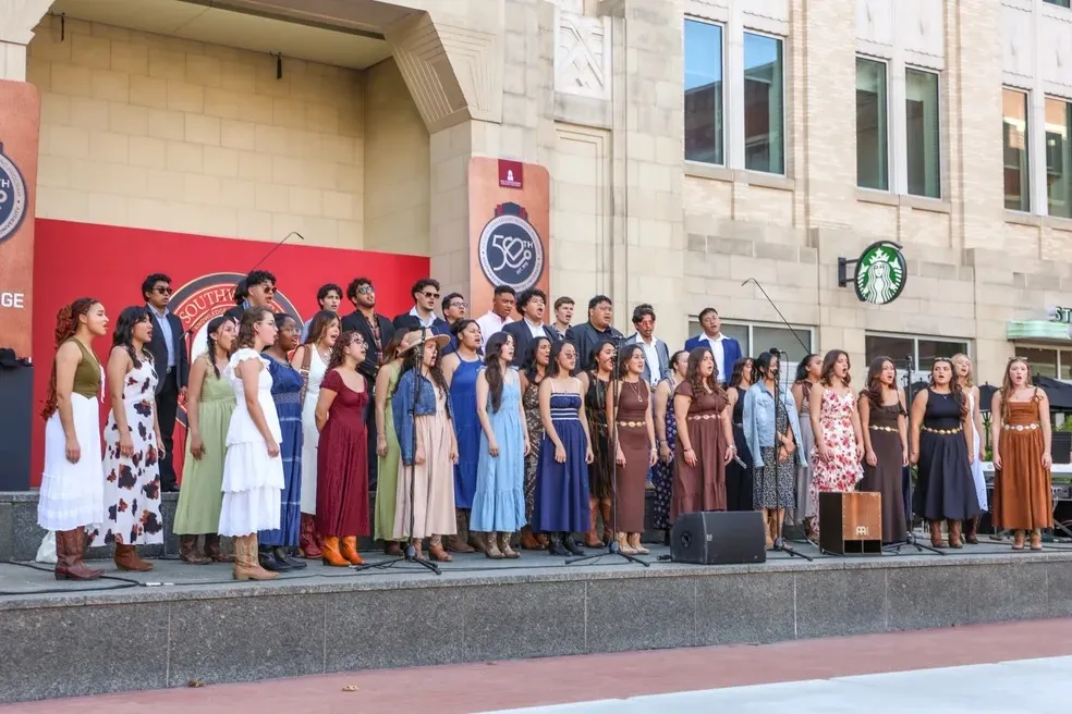 University Singers in dresses in front of building
