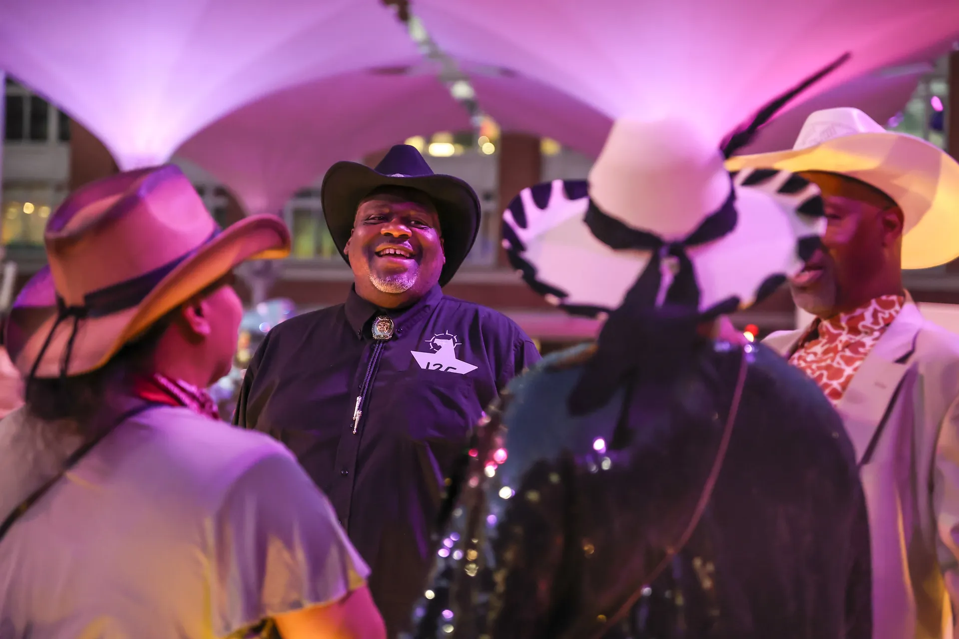 Four people conversing in a group wearing western hats