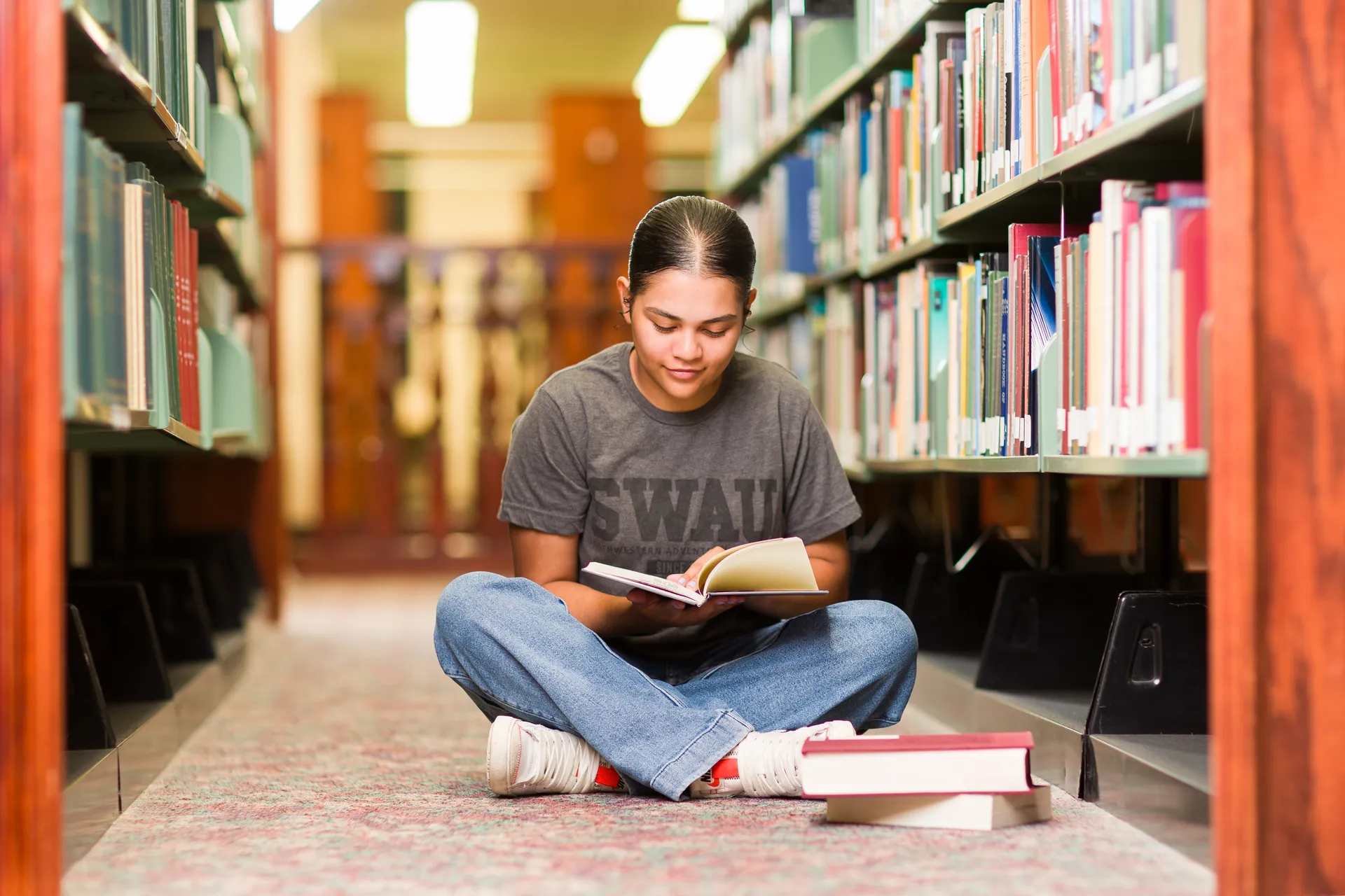 Person on floor of library reading book