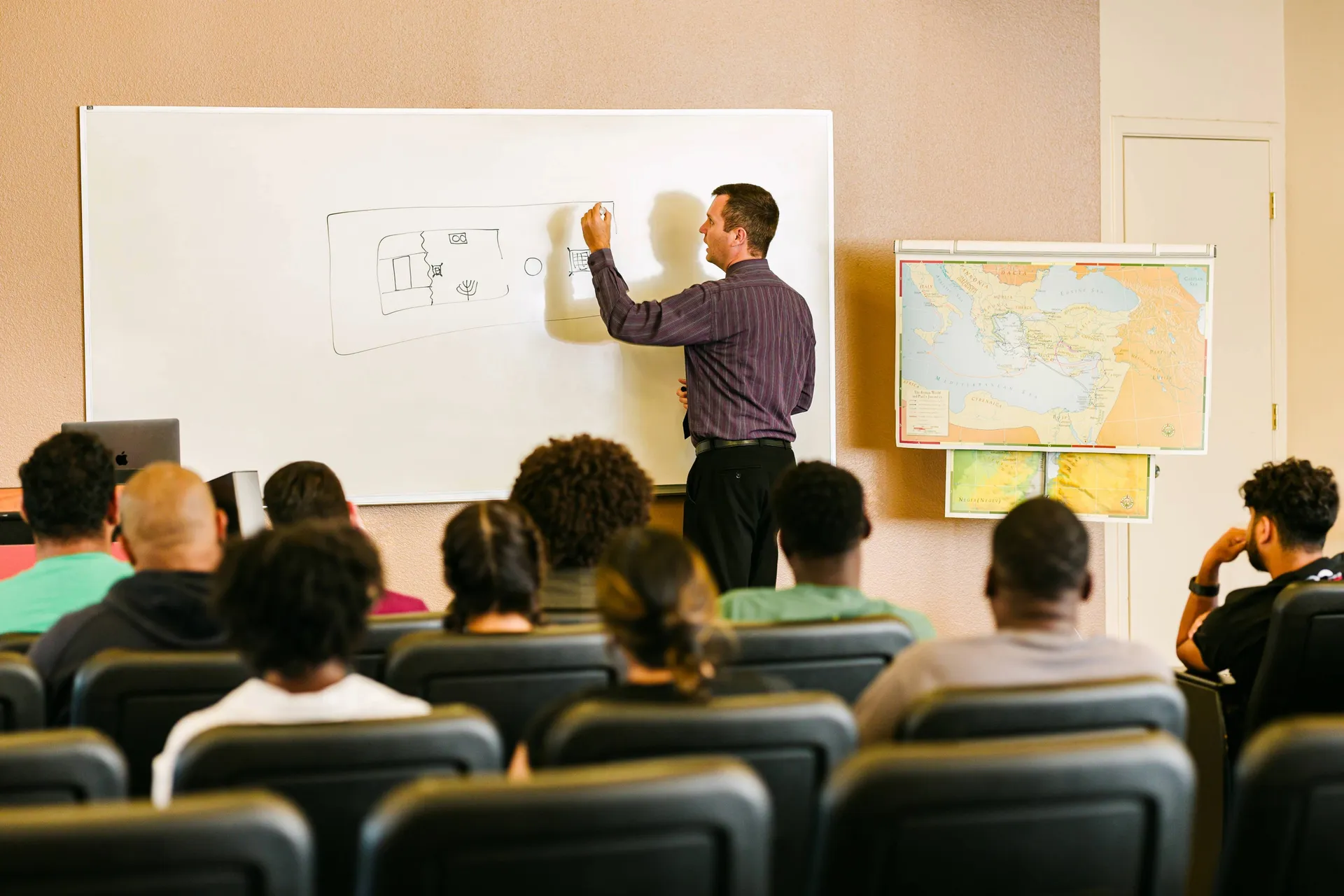 Teacher drawing on white board in front of students