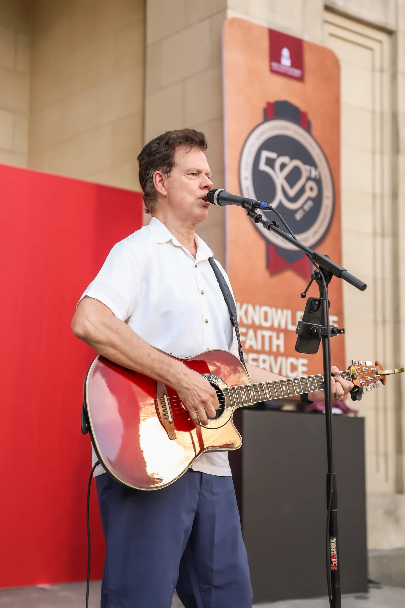 Man with guitar singing into a stand microphone