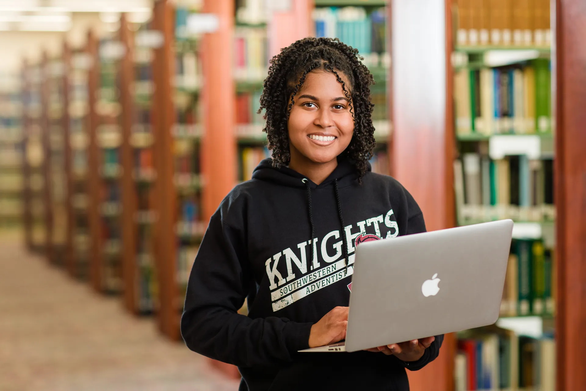 Student holding laptop in library