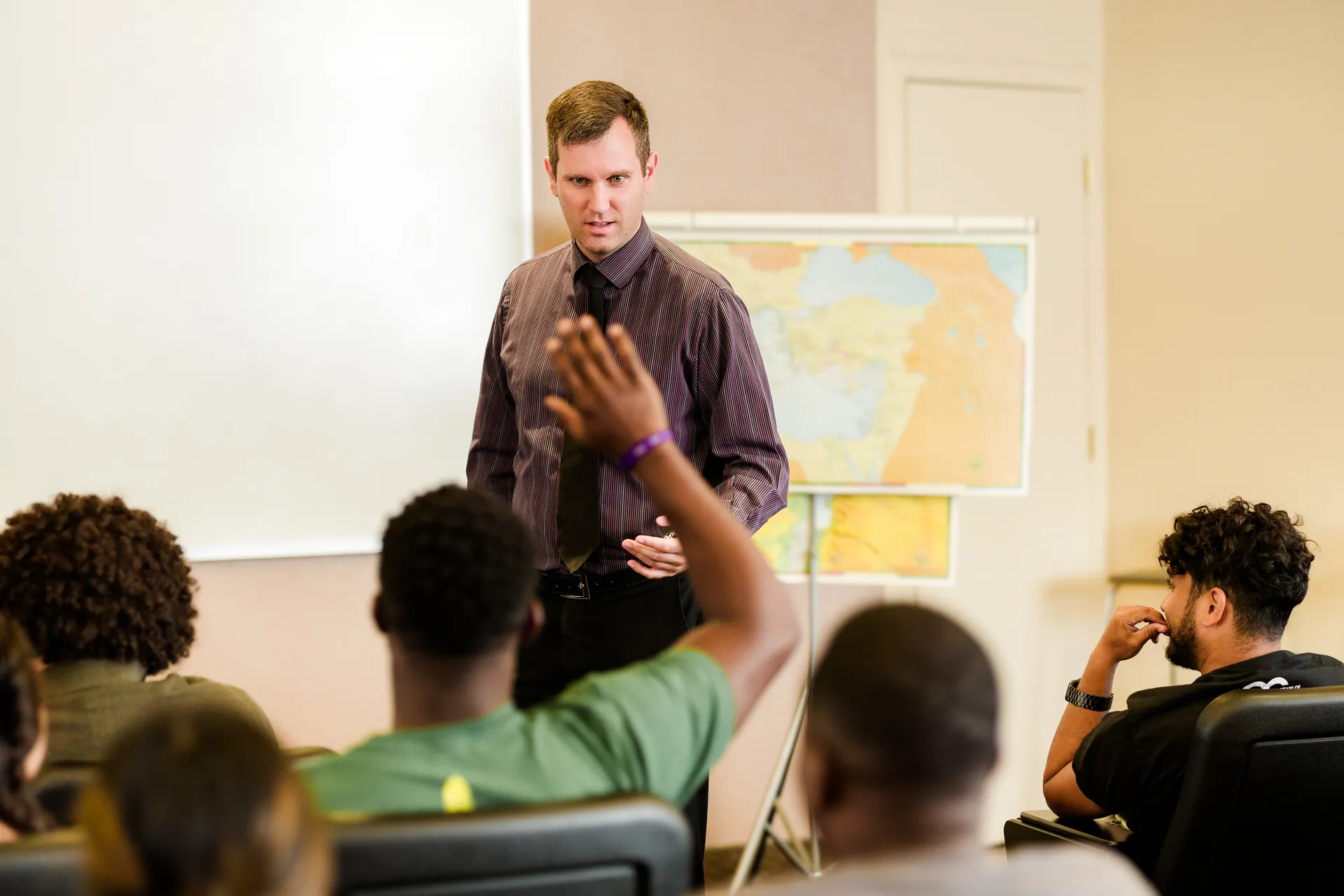 Student raising their hand and teacher looking at them