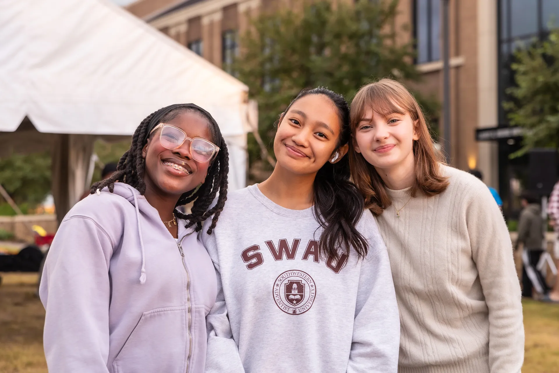 Three students huddled together smiling