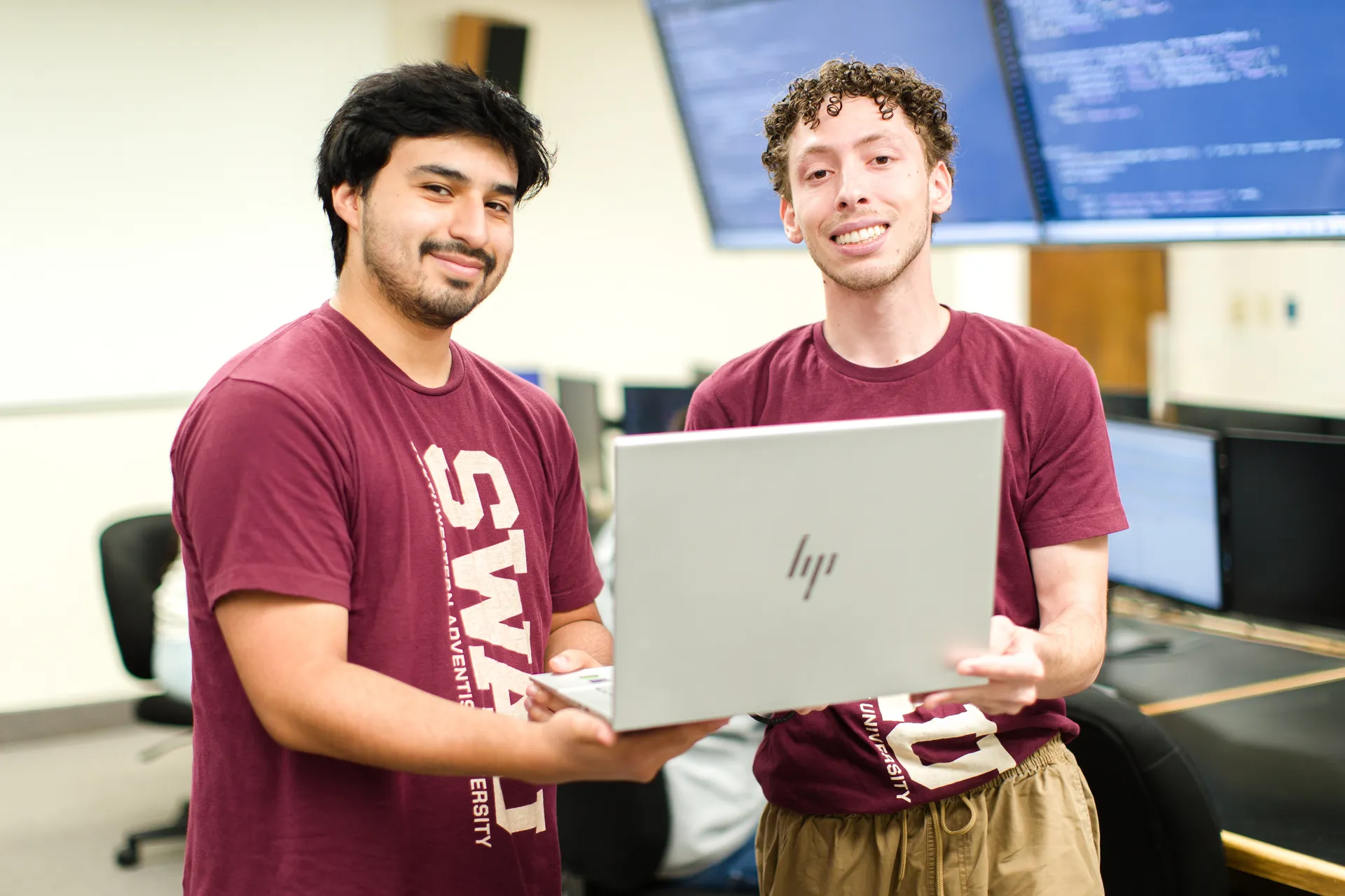 Two CS students holding laptop
