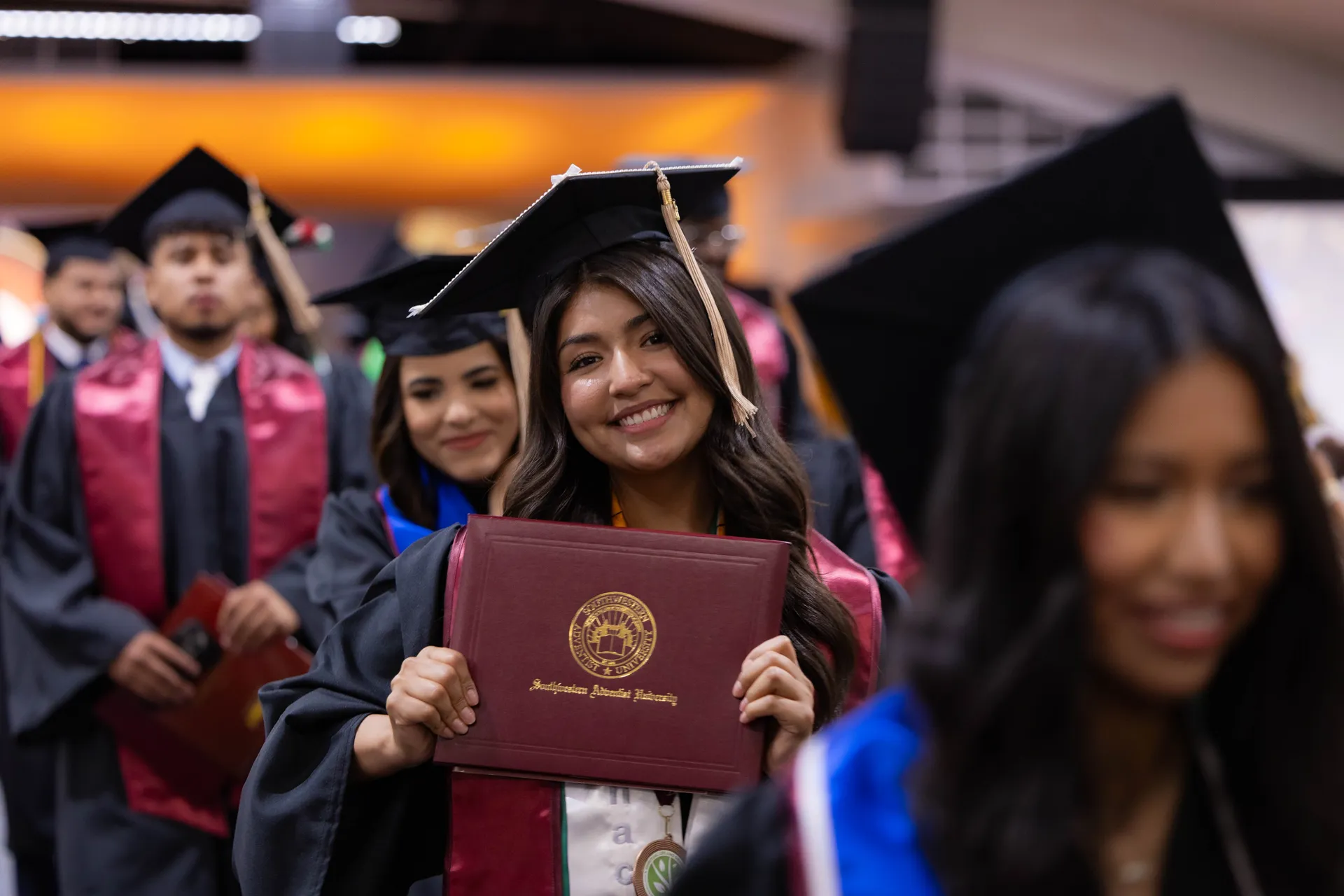 student standing in line for graduation holding diploma