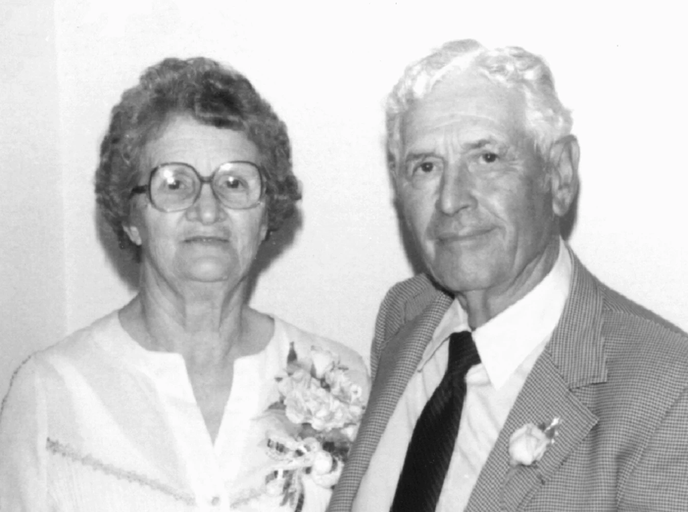 A female with short hair and glasses, smiles as she stands next to her husband