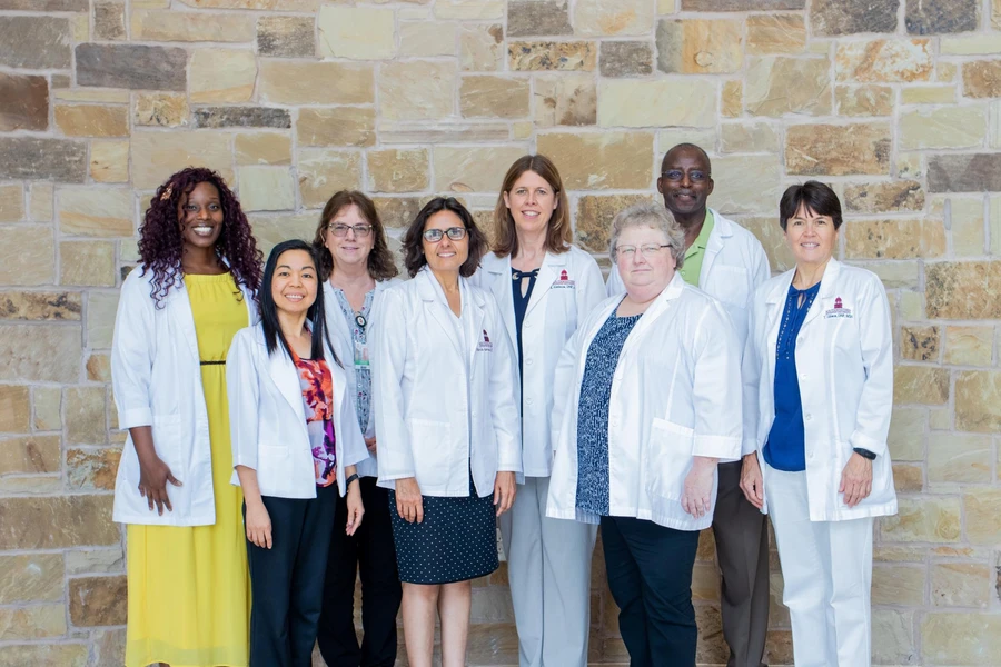 Dressed in their business professional clothes, the nursing administration smiles as they all match in white nursing coats
