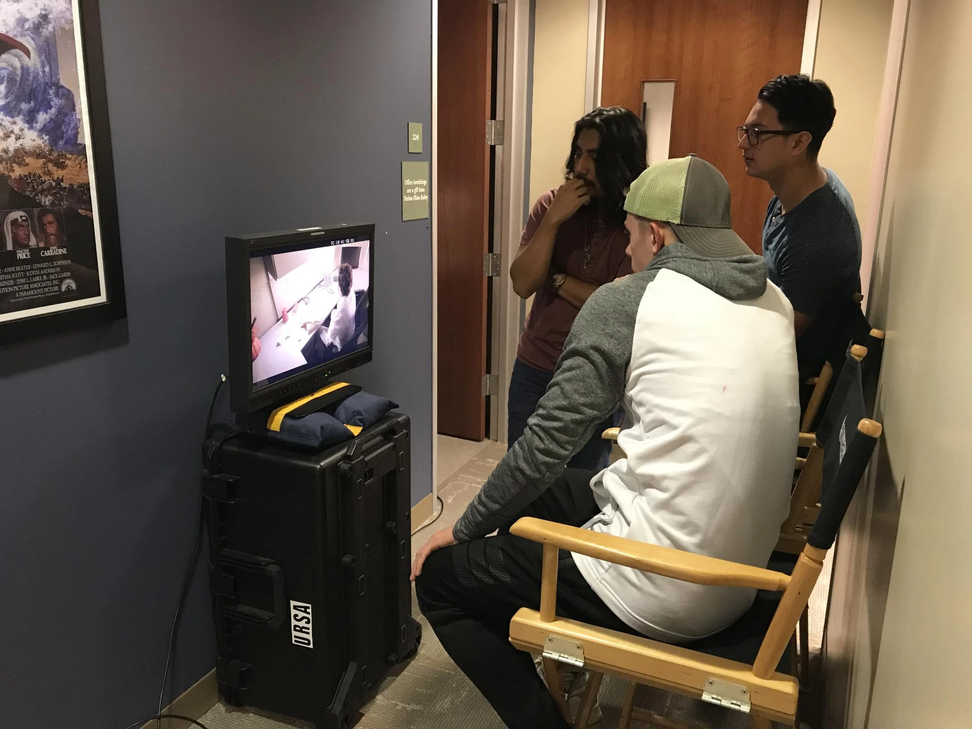 In front of three men is a monitar that shows what currently is being recorded in a different room
