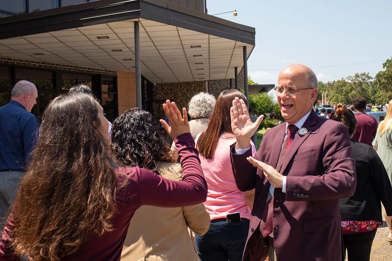 President Dr. Shaw, smiles and lifts his hand as he prepares to high five a student