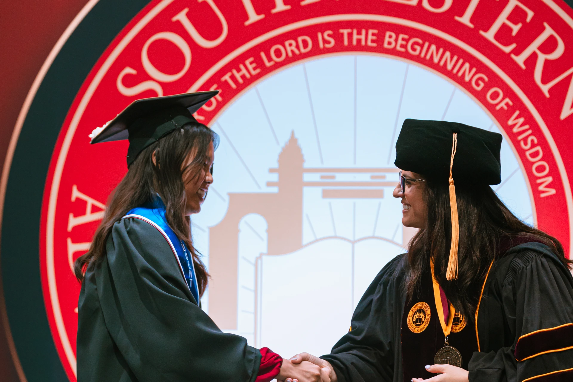 President Ana Patterson shakes graduates hand